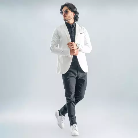 Hombre con blazer sport marfil slim fit, camisa negra, pantalón negro y zapatos deportivos blancos