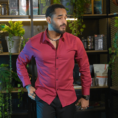 Hombre con camisa roja posando frente a estantería llena de plantas y artículos de cocina.