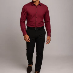 Hombre joven usando camisa vino tinto texturizada de corte slim fit, combinada con pantalón negro de vestir, cinturón negro y mocasines marrones, posando sobre fondo gris claro