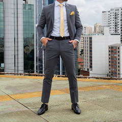 Hombre posando con traje formal slim fit gris oscuro, corbata amarilla y pañuelo en el pecho, en un entorno urbano.