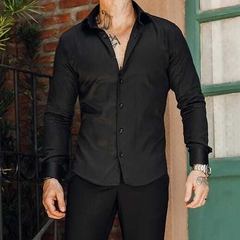 Hombre posando con una camisa slim fit negra, mostrando un estilo moderno y elegante.
