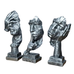 Escultura decorativa prateada representando trio de pensadores com gestos de não vejo, não escuto e não falo