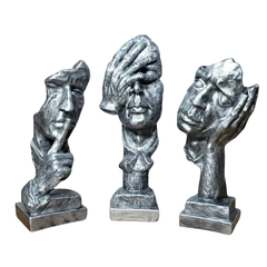 Escultura decorativa prateada composta por três bustos representando as expressões "Não vejo", "Não escuto" e "Não falo".