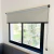Cortina roller Blackout Premium gris con accesorios negros instalada en ventana con marco negro y paisaje exterior visible