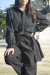 Mulher usando calça pantalona preta e camisa preta com botões, posando ao ar livre