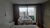 Vista de un dormitorio moderno con una cuna kiwi y un portatul y portamóvil, rodeado de una decoración contemporánea y ventanas grandes que ofrecen vista al exterior.