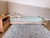 Minicama Astor de madera clara con colchón y almohadas, ubicada en una habitación con alfombra suave y paredes en tonos neutros.
