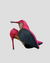 Um par de sapatos altos vermelhos da marca Schutz, com salto fino e bico alongado.