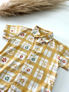Camisa alongada com estampa floral em fundo amarelo e quadrados brancos.