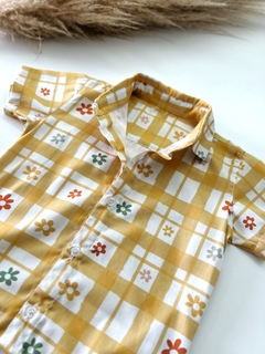 Camisa alongada com estampa floral em fundo amarelo e quadrados brancos.
