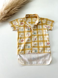 Camisa alongada com estampa floral em fundo amarelo e quadrados brancos.