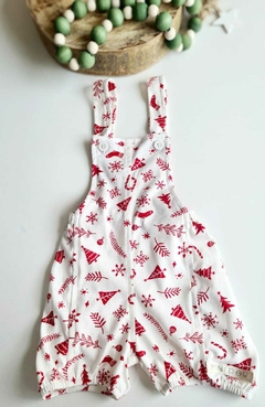 Jardineira natalina branca com estampas vermelhas de árvores de natal,  e outros símbolos natalinos.