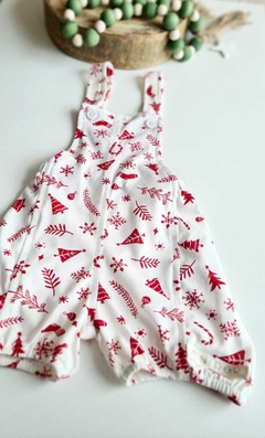 Jardineira natalina branca com estampas vermelhas de árvores de natal,  e outros símbolos natalinos.