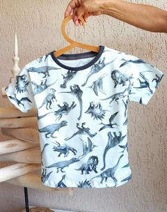 Camiseta infantil com estampa de dinossauros em tons de cinza.