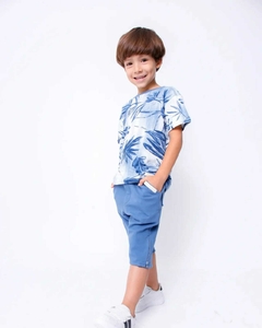 Camiseta floral azul com folhas, combinada com shorts azuis e tênis brancos.