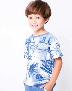 Camiseta floral azul com folhas, combinada com shorts azuis e tênis brancos.
