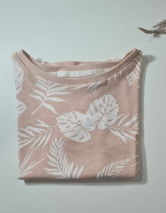 Camiseta floral dobrada na cor rosa com estampas de folhas brancas.
