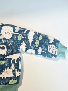 Jaqueta bomber azul com estampa de dinossauros e folhas verdes.