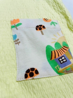 Jardineira bosque em amarelo com alças e bolsos decorados com estampas coloridas de natureza.