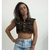 Colete jeans feminino curto estampado em modelo camuflado, com botões frontais e usado com calça jeans clara.