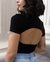 Modelo usando blusa cropped preta com recortes nas costas, destacando o design moderno e elegante.