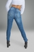 Calça skinny cintura alta jeans em lavagem clara, vista de trás, combinada com botas de salto alto.